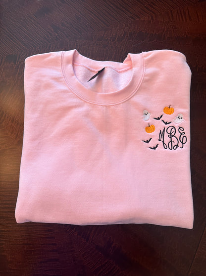 Folded pink embroidered sweatshirt with monogram and ghost-pumpkin embroidery — personalized spooky season crewneck