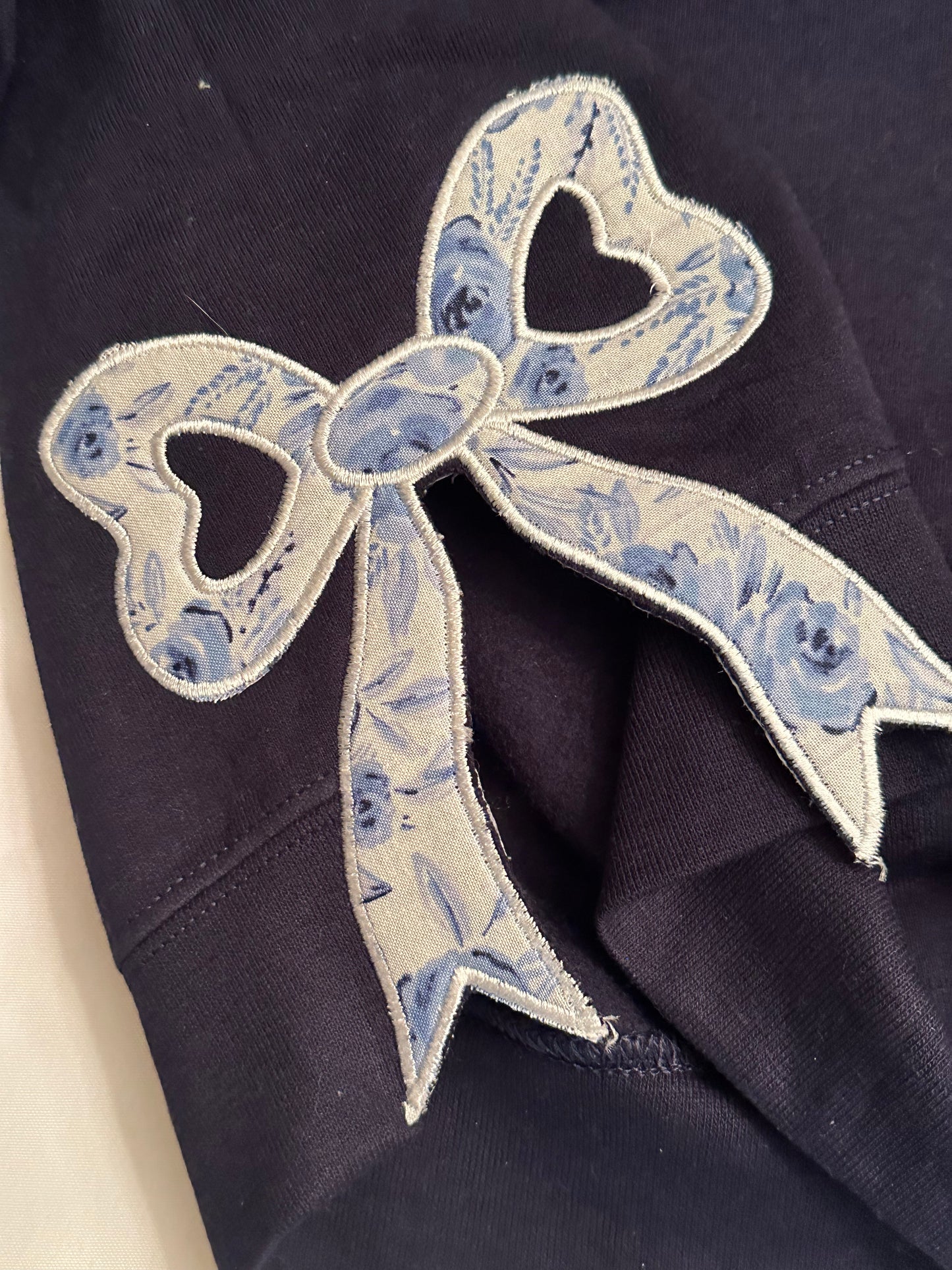 Navy blue fabric with a decorative blue floral bow patch