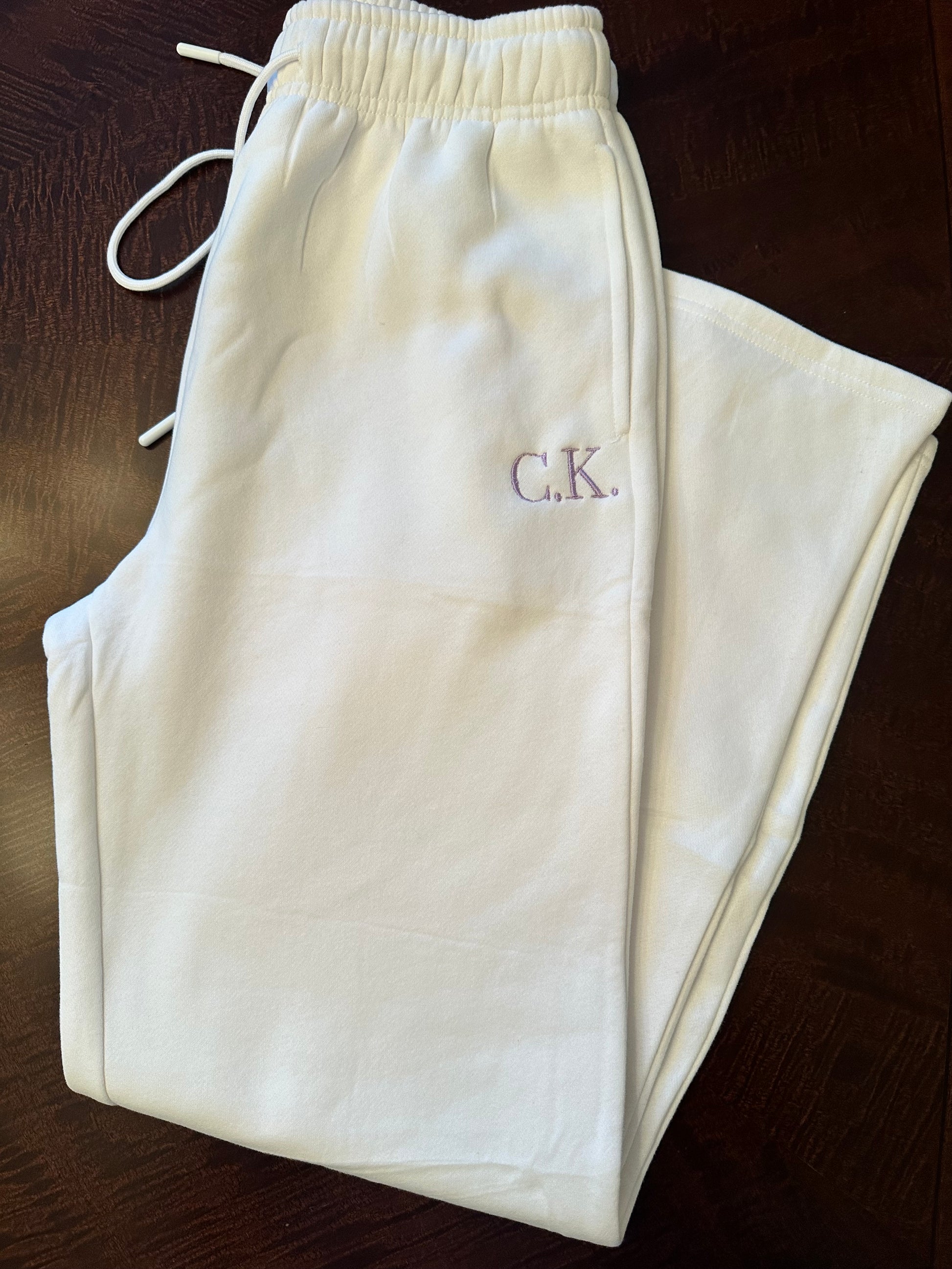 white wide leg bridal sweatpants with elastic waistband and customizable embroidered initials on hip, shown folded on wooden surface