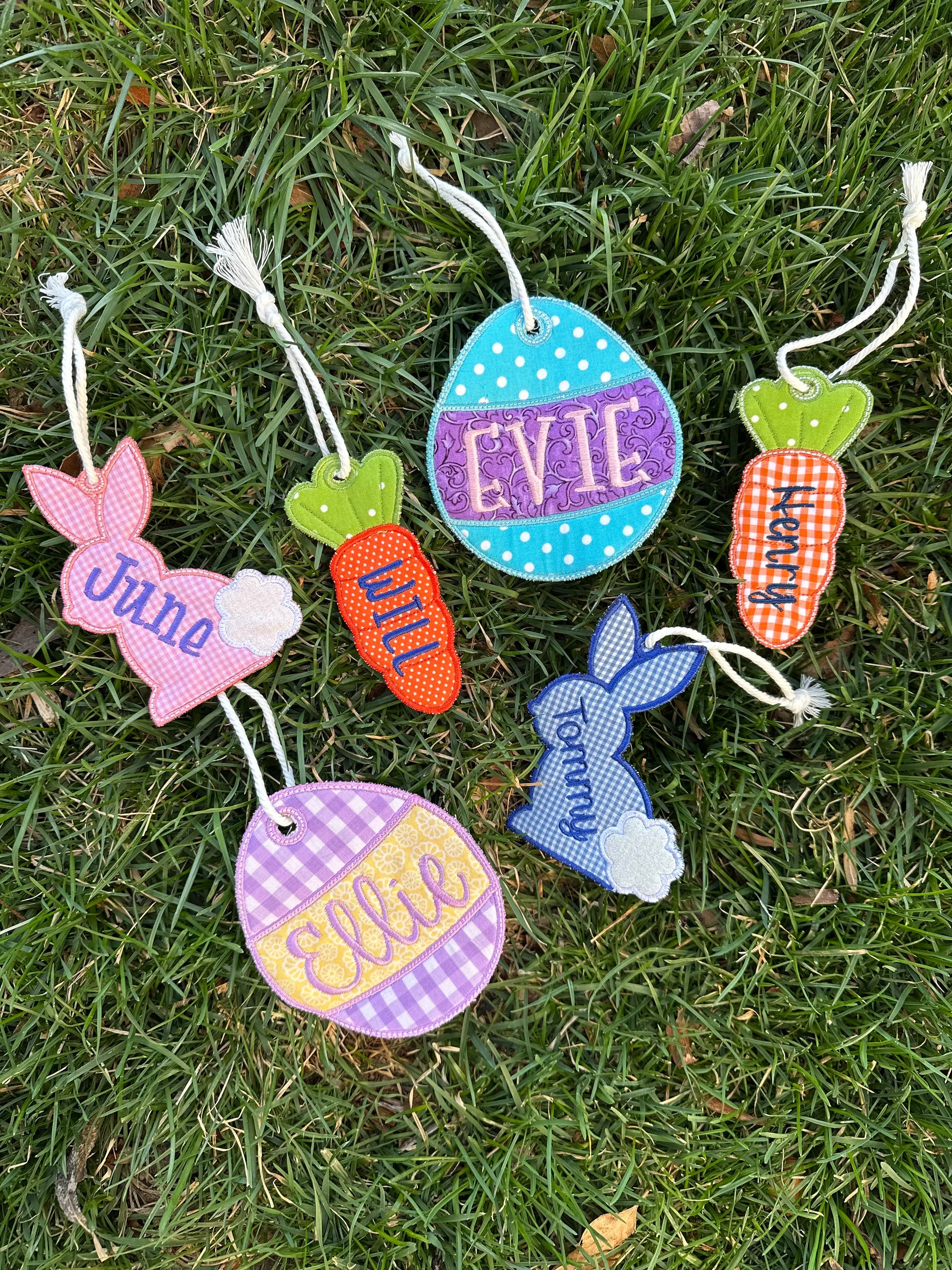 Personalized embroidered Easter basket tags in bunny, carrot, and Easter egg shapes, featuring custom names in colorful fabrics with string ties – handmade Easter decorations perfect for kids' baskets.