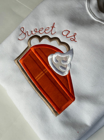 Embroidered design of a slice of pie with text on a white background