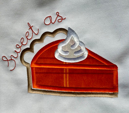 Embroidered patch of a slice of pie with whipped cream and 'sweet as' text on a fabric background