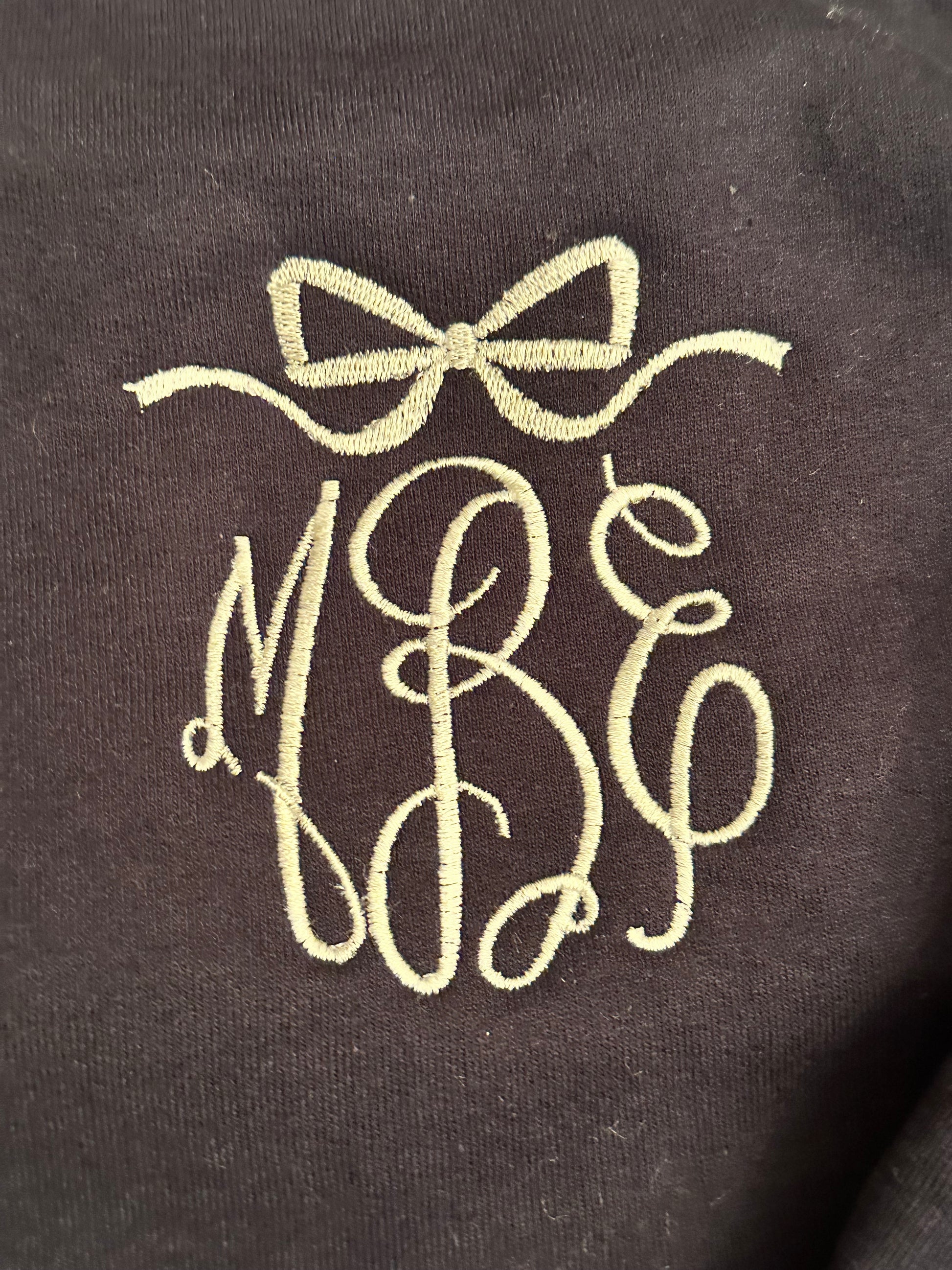 Monogram with bow frame in white thread on navy sweatshirt